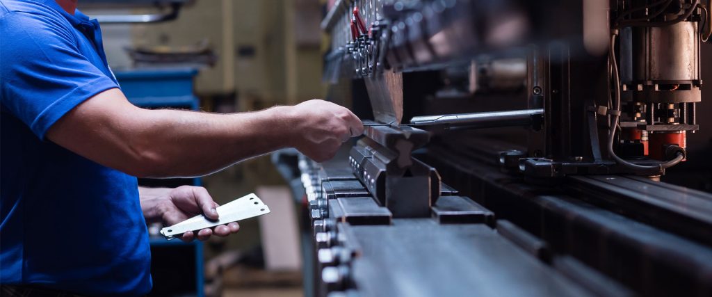 Worker holding metal plate in manufacturing plant